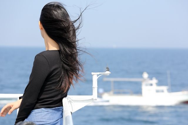 海を見つめるロングヘアの女性