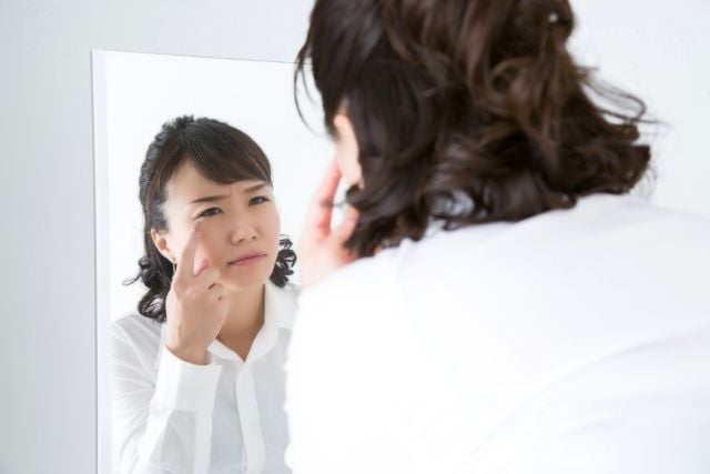 鏡で目の不快感を確認する女性